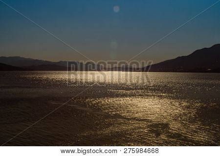 Sunshine Glimmering On Yedang Reservoir During Blue Hour With Mountains In Background. Located In Ye