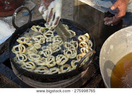 Close Of A Hand Frying Jalebi In Hot Oil In A Street Village Market In A Stove In Daylight