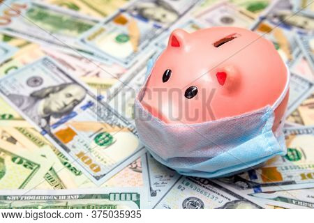 Piggy Bank In A Mask On A Background Of American Currency.the Concept Of Coronavrius Epidemic