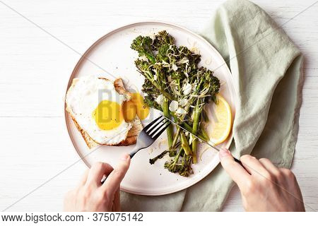 Roasted Broccolini, Lemon, Fried Egg With Tost On The Plate On The Table Decorated With Napkin. Top 