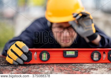 Asian Maintenance Worker Man Holding Red Aluminium Spirit Level Tool Or Bubble Levels At Constructio