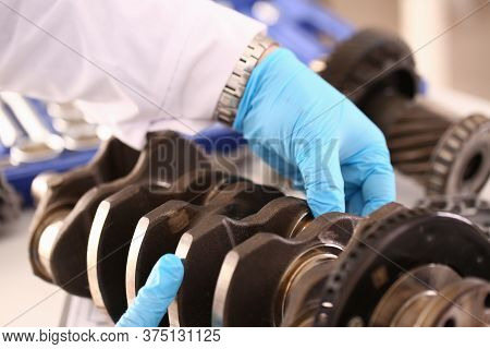 Close Up Of Mechanic Wearing Protective Gloves And Repairing A Crankshaft From A Car