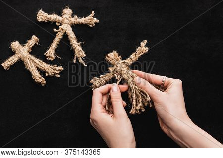 Top View Of Witch Holding Voodoo Doll On Black
