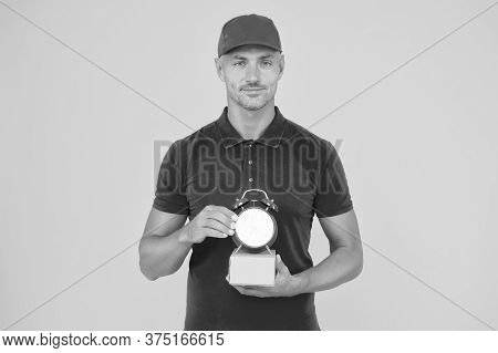On Time Delivery. Delivery Man Yellow Background. Courier Hold Clock And Box. Parcel Delivery Servic