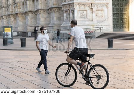 Milan, Italy - May 4, 2020: Man Riding Bicycle On Duomo Square. Italy Enters Second Phase Of Coronav
