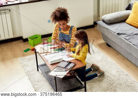 Caucasian Little Girl Spending Time With African American Baby Sitter. They Are Drawing, Learning To