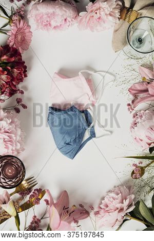 Cultery, glasses and flowers frame with protective masks on white background - coronavirus pandemic concept, outbreak lifestyle, flat lay