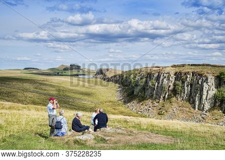 11 August 2018: Hadrians Wall, Northumberland, Uk - Group Of Gray Haired Seniors Sitting On The Gras