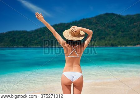 Back View Of Young Happy Woman In White Bikini And Straw Hat Raised Hand Up Enjoy Her Summer Vacatio