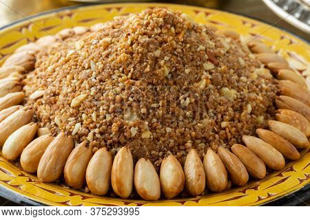 Dish with traditional Moroccan homemade sellou decorated with roasted almonds close up
