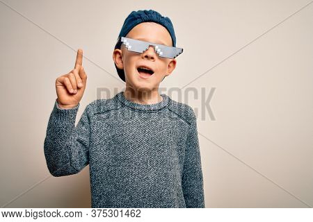 Young little caucasian kid wearing internet meme thug life glasses over isolated background pointing finger up with successful idea. Exited and happy. Number one.