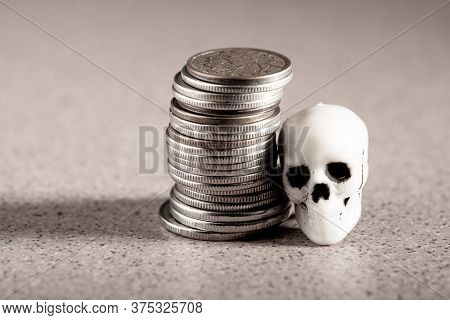 Metal Coins Piled In A Stack And A Human Skull. Wealth Endangering Health