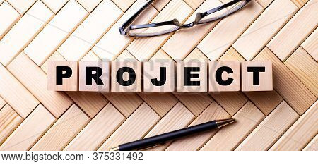 The Word Project Is Written On Wooden Ubiks On A Wooden Background Near A Pen And Glasses. Business 