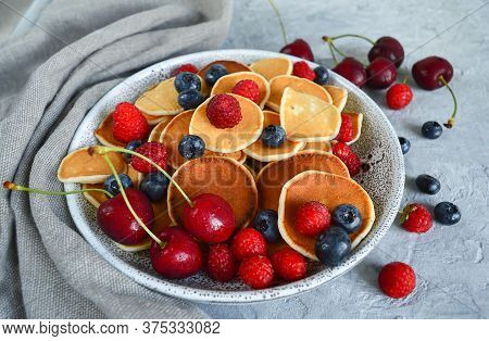 Pancake Cereal, Mini Pancakes In A Plate With Blueberries, Raspberries, Cherries. Healthy Nutrition.