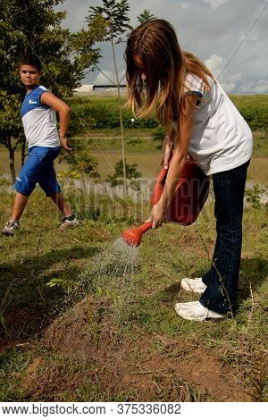 Eunpolis, Bahia Brazil - June 19, 2009: Child Is Seen Using Watering Can To Water Plant In The City 