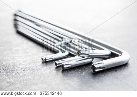 Metal torx screwdrivers on black table.