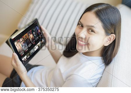 Bangkok, Thailand  - July 06, 2020: A Young Woman Is Using Netflix Application On Tablet In Her Hous