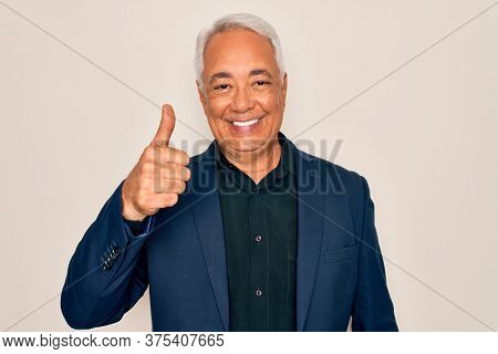 Middle age senior grey-haired handsome man wearing elegant business jacket doing happy thumbs up gesture with hand. Approving expression looking at the camera showing success.