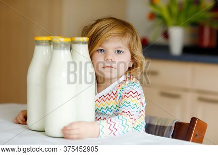 Adorable Toddler Girl Drinking Cow Milk For Breakfast. Cute Baby Daughter With Lots Of Bottles. Heal