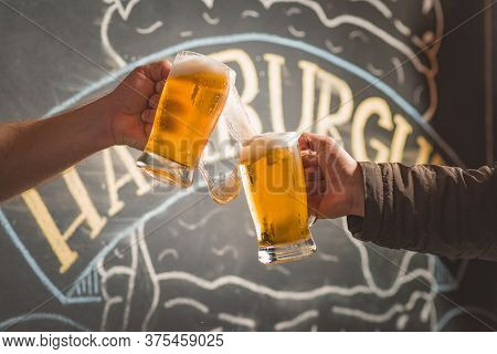 Two People Toasting With Mugs Full Of Chopp