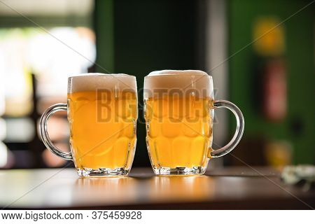 Two Mugs Full Of Chopp, With Chopp Pilsen On A Rustic Table