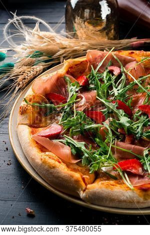 Pizza With Prosciutto Parma Ham, Arugula Salad Rocket And Strawberries On Wooden Background Italian 