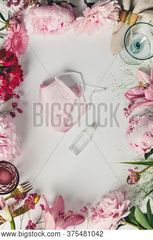 Cultery, glasses and flowers frame with protective masks on white background - coronavirus pandemic concept, outbreak lifestyle, flat lay