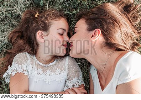Mom And Her Daughter Lying On The Grass, Eskimo Kissing. Parents Children Relationship
