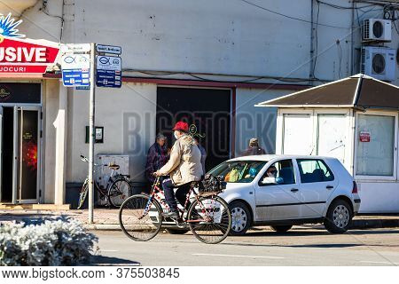 Old Man Wearing Surgical Mask And Riding A Bike On Sunny Day In Downtown Of Lugoj, Romania, 2020