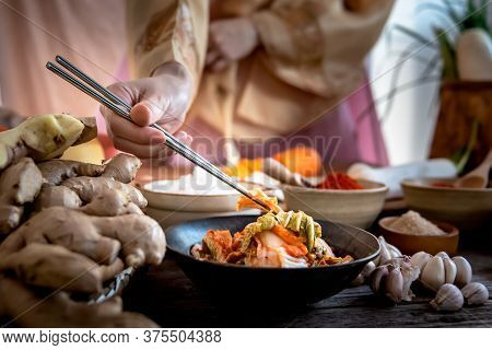 Blurred Soft Images Of Woman Wearing A Traditional Hanbok, Using Chopsticks To Eat Kimchi Which Made