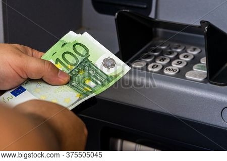 Depositor Withdraws Euro From Atm Cash Money Machine. Man Hand Holding Euro Banknotes At The Atm Mac