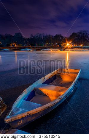 Frozen Lake With A Boat In The Winter Shot During Night In A Park In Bucharest Romania With A Bridge