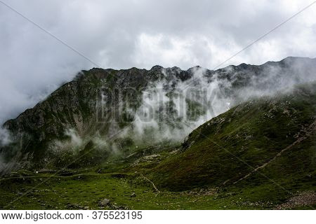 White Clouds, Blue Sky, Green Pastures And Spikes Of Granite Rock In The Lagorai In The Trentino Alp