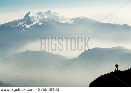 Man Reaching Summit Enjoying Amazing Sunrise In The Mountains. Backlight Sunlight With Beautiful Len
