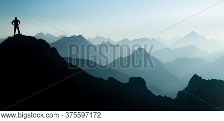 Man Reaching Summit After Climbing And Hiking Enjoying Freedom And Looking Towards Mountains Silhoue