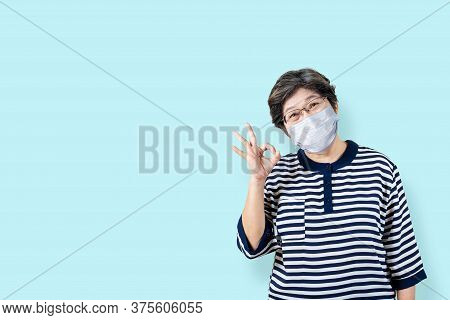 Portrait Of Happy Senior Asian Woman Wear Face Mask And Gesture Or Showing Hand Ok And Looking At Ca
