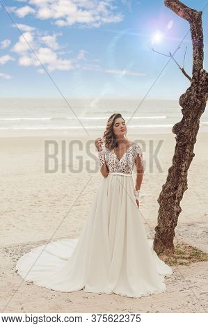 Beautiful Bride In Her Wedding Dress Posing For Photos On The Beach.