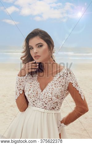 Beautiful Bride In Her Wedding Dress Posing For Photos On The Beach.