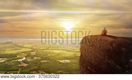 Buddhist Monk In Meditation At Beautiful Sunset Or Sunrise Background On High Mountain
