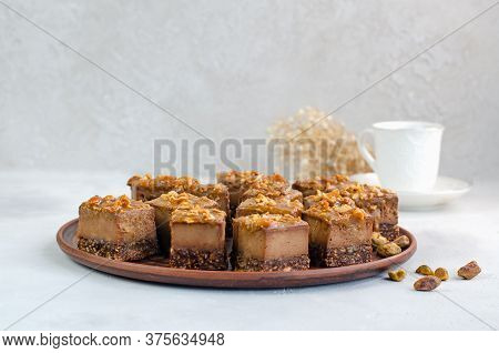 Raw Vegan Dessert. Chocolate Bars With Nuts And Dates On A White Background With A Cup Of Tea. Healt