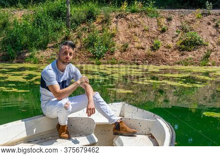 Young Man In White Pants And Modern Styling Posing In The Freshwater Pond Of Clot De La Mare De Deu 