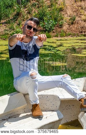 Young Man In White Pants And Modern Styling Posing In The Freshwater Pond Of Clot De La Mare De Deu 