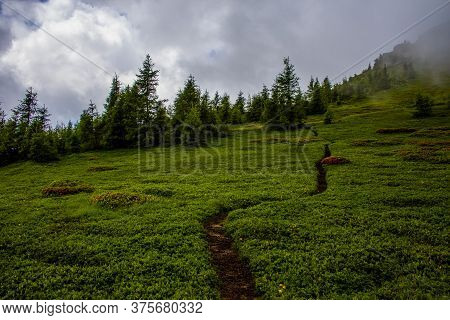 Path Climbs Between The Alpine And Granite Rocks Of Lagorai With Cloudy Skies Near Lake Levico In Tr