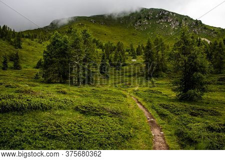 Path Climbs Between The Alpine And Granite Rocks Of Lagorai With Cloudy Skies Near Lake Levico In Tr