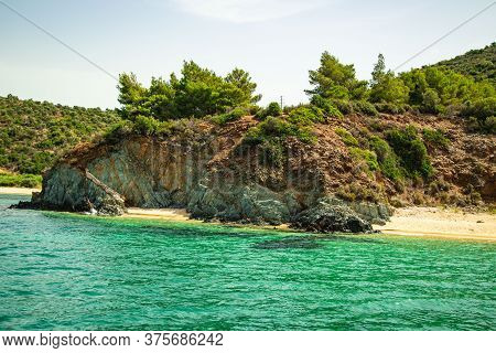 A Beach In The Greek Archipelago In Summer, A Great Azure, A Clear Sky, Forest And Mountains