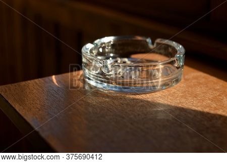 Ashtray With A Cigarette Butt On Wooden Surface.