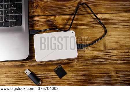 External Hdd Connected To Laptop Computer, Sd Memory Card And Usb Flash Drive On A Wooden Desk. Top 