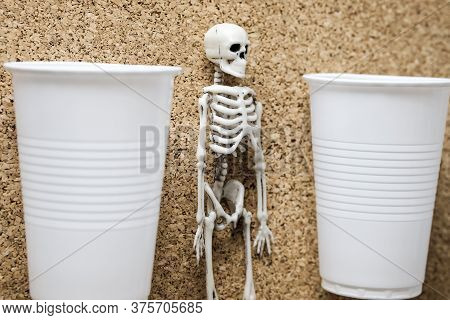 Plastic Container And Plastic Toy Skeleton On A Cork Background. Mortal Danger Of Plastic And Enviro