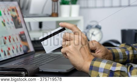 Asian Man Holding Credit Card And Typing Information On Internet With Laptop At Home, Online Shoppin