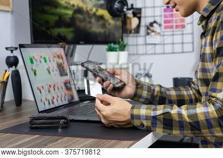 Asian Man Holding Credit Card And Typing Information On Internet With Laptop At Home, Online Shoppin